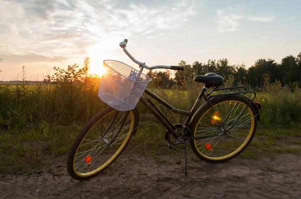 Afbeelding van het prachtige landschap met fiets bij zonsondergang, klassieke fiets met een mandje — Stockfoto