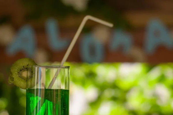 Green cocktail with straw and slice of kiwi, Hawaiian cocktail