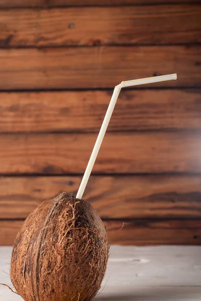 Coco pelado con paja para beber sobre mesa de madera — Foto de Stock