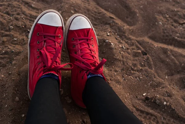 Patas de mujer en zapatos rojos en la arena, relajándose en la playa —  Fotos de Stock