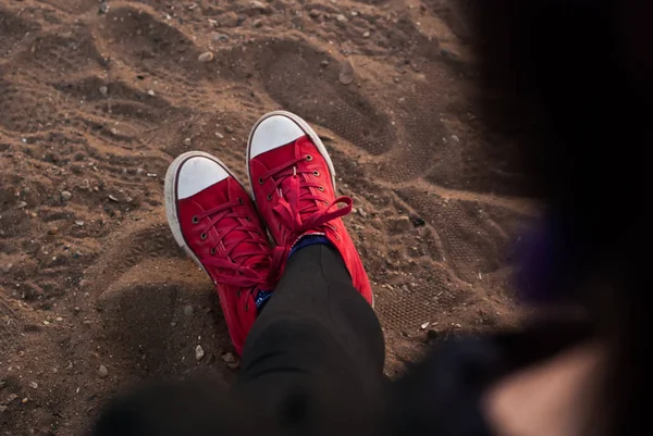 Pernas de mulher em sapatos vermelhos na areia, relaxando na praia — Fotografia de Stock