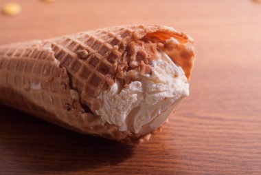 Ahşap bir masa üzerinde bir gözleme koni vanilyalı dondurma. Yaz parlak güneş.