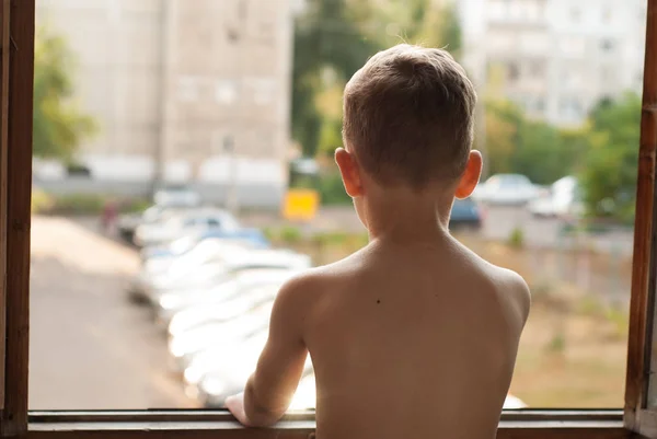 Одинокий мальчик смотрит в окно , — стоковое фото