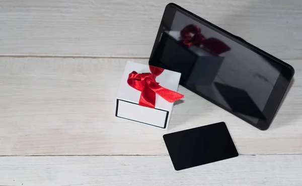 Tablet, white box with a red ribbon and card,