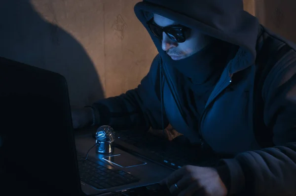 Hacker in a hood in a dark room, the intruder breaks into a system — Stock Photo, Image