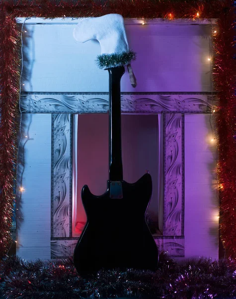 Чорна гітара в білому панчосі проти каміна . — стокове фото