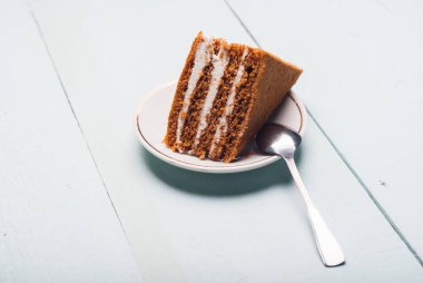 Beyaz bir tabak ve küçük bir kaşık katmanlı tatlı,