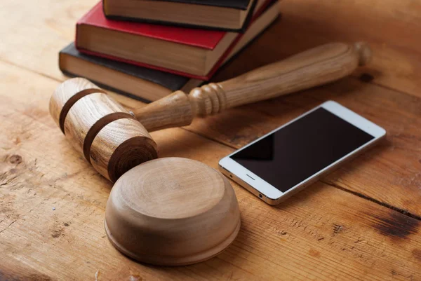 Smartphone, hakimin tokmak ahşap arka plan üzerinde.