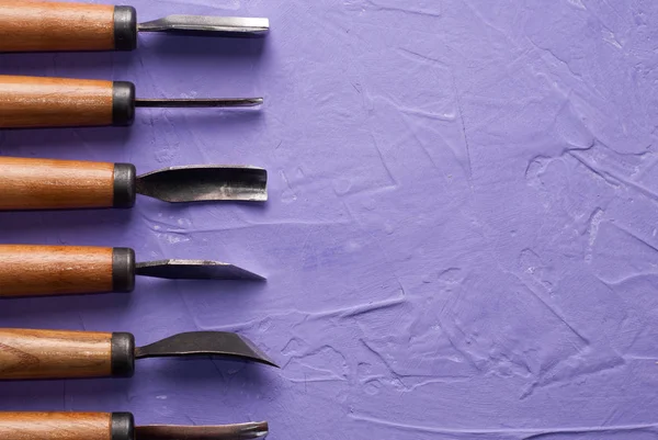 Herramientas para tallar en madera sobre fondo texturizado púrpura , — Foto de Stock
