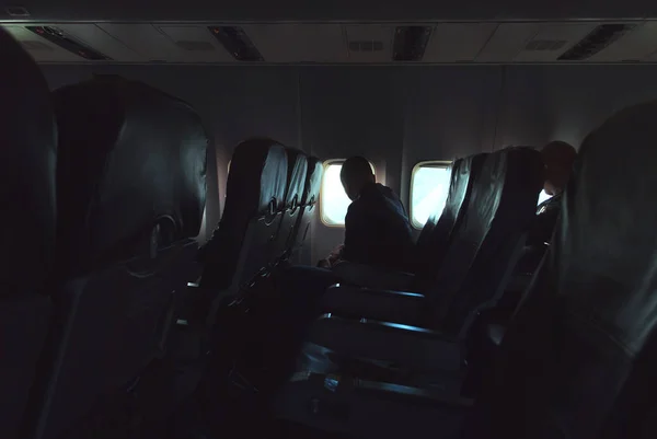 Пасажир виглядає з вікна, яскраве світло у вікнах літака. — стокове фото
