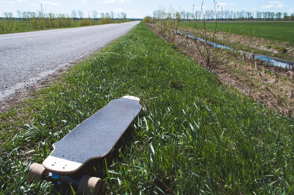 Longboard im Gras neben der Straße, — Stockfoto