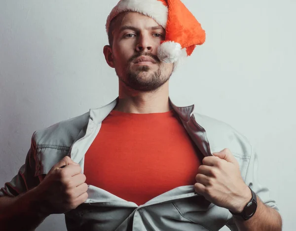 Um homem de chapéu de Pai Natal rasga-lhe a camisa. Herói de vermelho. O conceito de Papai Noel um super-herói — Fotografia de Stock