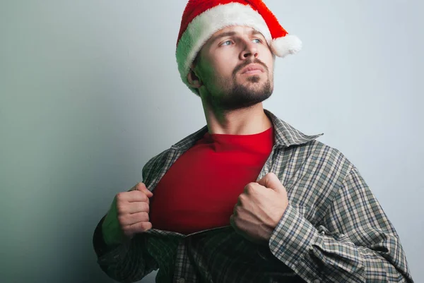 O jovem Pai Natal rasga a camisa no peito como um super-herói. o homem do chapéu de Pai Natal , — Fotografia de Stock