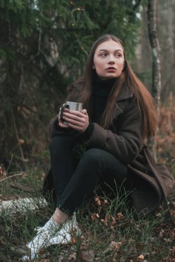 Ormandaki kız demir bardağı elinde tutuyor. Kış ormanlarında karsız bir model.,