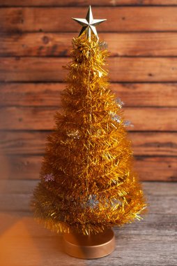 Ahşap zemin üzerinde yıldız olan sarı Noel ağacı. Yapay Noel ağacı ve bokeh,