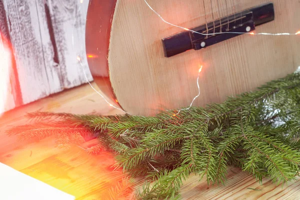 Tahta arka planda çelengi olan eski bir akustik gitar, Noel gitarı., — Stok fotoğraf