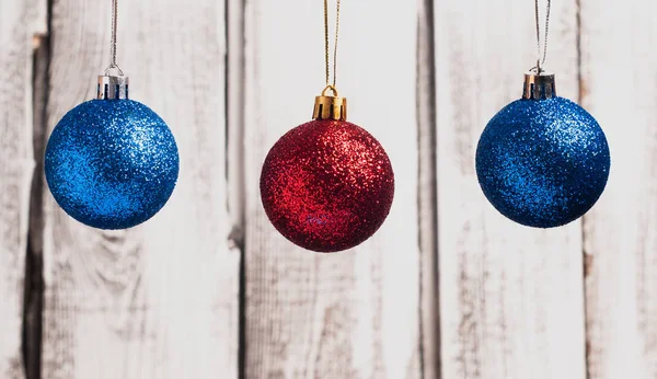 Bolas de Natal vermelho e azul penduradas em cordas no fundo de madeira , — Fotografia de Stock