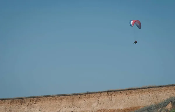 Parapente contra um céu limpo. Saltar de um penhasco em um planador , — Fotografia de Stock