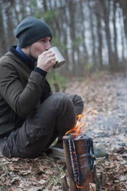 Bir turist ateşin yanında çay içer. Yürüyüş konsepti.,