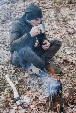 Bir turist ateşin yanında çay içer. Yürüyüş konsepti.,