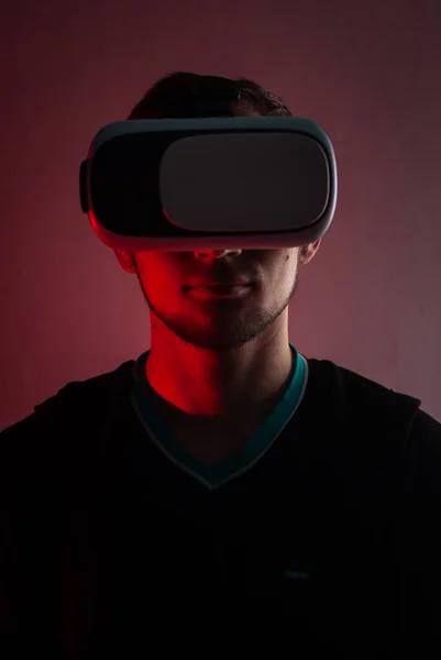 A hacker in the VR glasses in red light, the gamer in the virtual space, — Stock Photo, Image