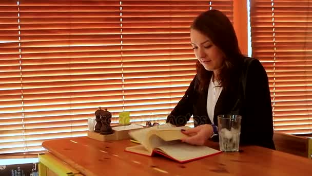 Menina folheando através de um livro na mesa — Vídeo de Stock