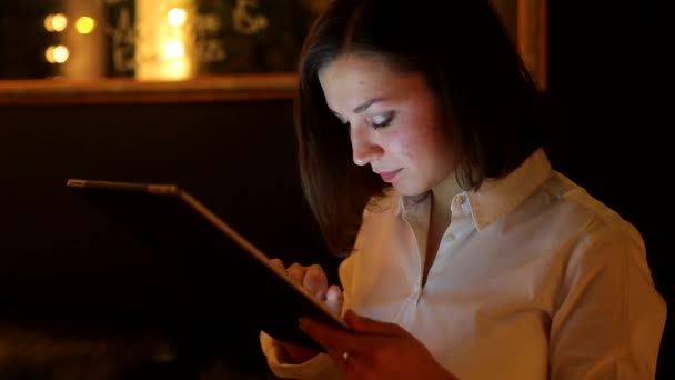 Nahaufnahme einer Frau, die in einem Café auf ihr digitales Tablet lächelt — Stockvideo