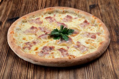 Eritilmiş peynirli sıcak İtalyan pizzası ve ahşap arka planda domuz pastırması şeritleri. 