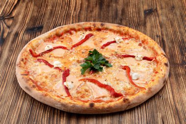 Eritilmiş peynirli fırınlanmış deniz ürünleri pizzası ve ahşap arka planda ketçap.