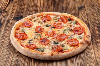 Çok sıcak ve baharatlı pizza, jalapeno, pepperoni ve ahşap zemin üzerinde kırmızı soğan.