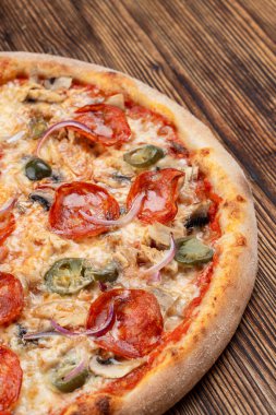 Çok sıcak ve baharatlı pizza, jalapeno, pepperoni ve ahşap zemin üzerinde kırmızı soğan.