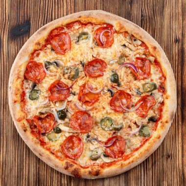 Çok sıcak ve baharatlı pizza, jalapeno, pepperoni ve ahşap zemin üzerinde kırmızı soğan.