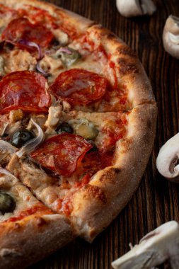 Sıcak ve baharatlı pizzaya yakın, jalapeno, pepperoni ve koyu ahşap arka planda kırmızı soğan.