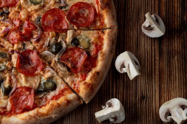 Sıcak ve baharatlı pizzaya yakın, jalapeno, pepperoni ve koyu ahşap arka planda kırmızı soğan.