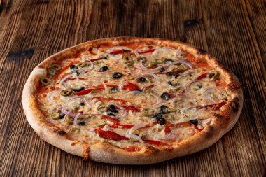 Kırmızı soğanlı İtalyan pizzası, siyah ve yeşil zeytin, erimiş peynir ve arka planda ketçap.