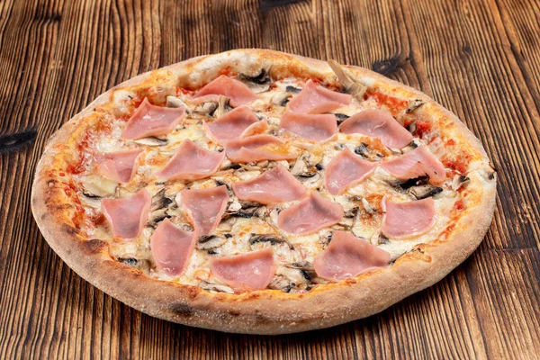 Altın hamurlu fırında pizza, jambon, şampiyonlar ve erimiş peynir.