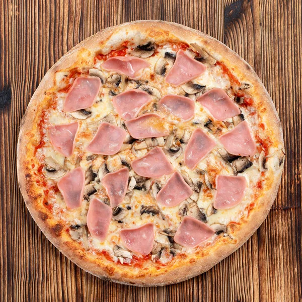 Pizza assada com crosta dourada, presunto, champinhons e queijo derretido — Fotografia de Stock