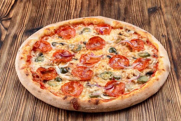 Çok sıcak ve baharatlı pizza, jalapeno, pepperoni ve ahşap zemin üzerinde kırmızı soğan.