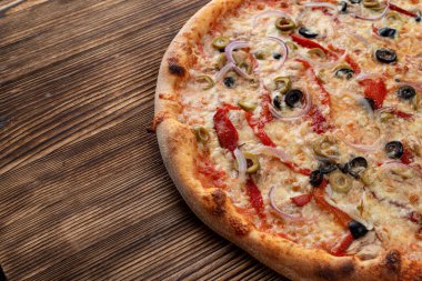Kırmızı soğanlı İtalyan pizzası, siyah ve yeşil zeytin, erimiş peynir ve arka planda ketçap.