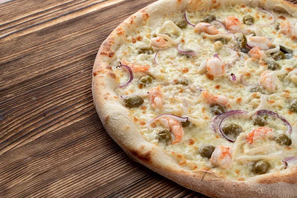 Karidesli İtalyan deniz ürünleri pizzası ve rustik desenli arka plan kapari.