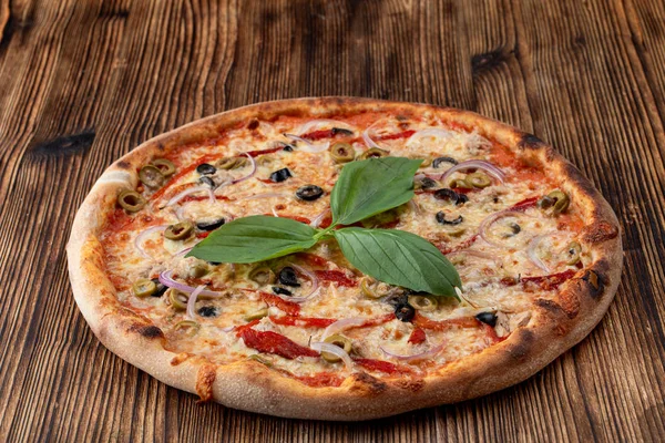 Pizza italiana con cebolla roja, aceitunas negras y verdes, queso derretido y ketchup sobre fondo rústico texturizado — Foto de Stock