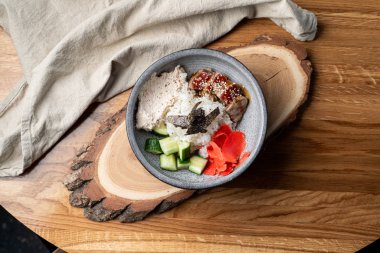 Bıçak ve çatalla ahşap masada pirinç, zencefil ve salatalık dolu yılan balığı kasesi.