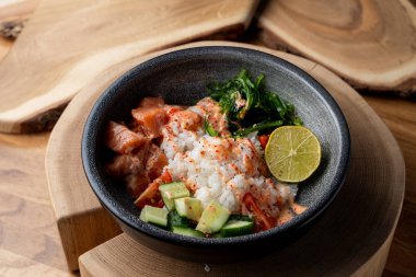 Çiğ somon kabı, beyaz pirinç, chuka ve salatalık ahşap kırsal masada. 