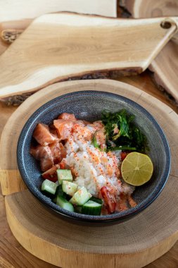 Çiğ somon kabı, beyaz pirinç, chuka ve salatalık ahşap kırsal masada. 