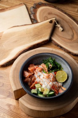 Çiğ somon kabı, beyaz pirinç, chuka ve salatalık ahşap kırsal masada. 