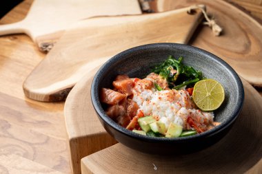 Çiğ somon kabı, beyaz pirinç, chuka ve salatalık ahşap kırsal masada. 