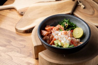 Çiğ somon kabı, beyaz pirinç, chuka ve salatalık ahşap kırsal masada. 