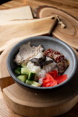 Beyaz pirinçli ton balığı kasesi, ahşap kırsal masada zencefil ve salatalık. 