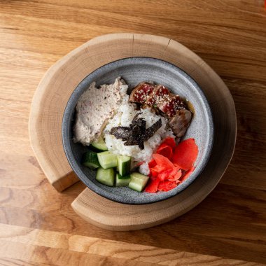 Beyaz pirinçli ton balığı kasesi, ahşap kırsal masada zencefil ve salatalık. 