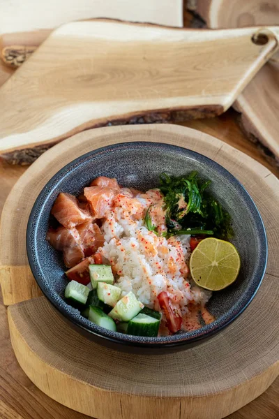 Çiğ somon kabı, beyaz pirinç, chuka ve salatalık ahşap kırsal masada. 